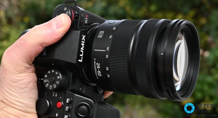 Objectif Panasonic Lumix S 24-60mm f/2.8 monté sur boîtier Lumix S1 II, vue 3/4 avant, tenu en main, fond végétal