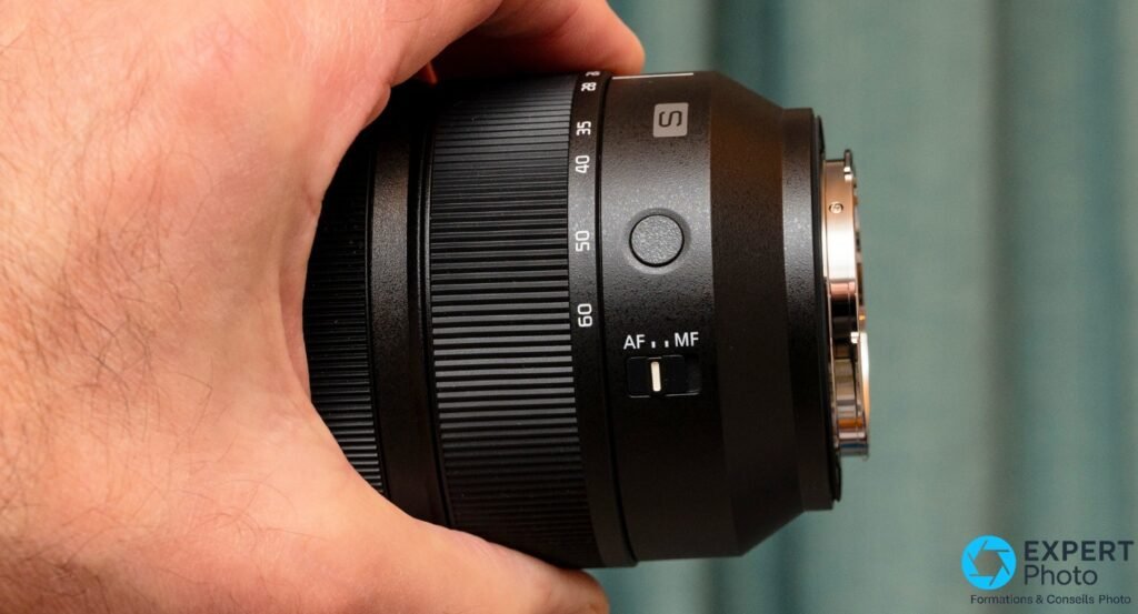 Objectif Panasonic Lumix S 24-60mm f/2.8 seul, profil côté commutateur AF/MF et monture L-Mount, tenu en main