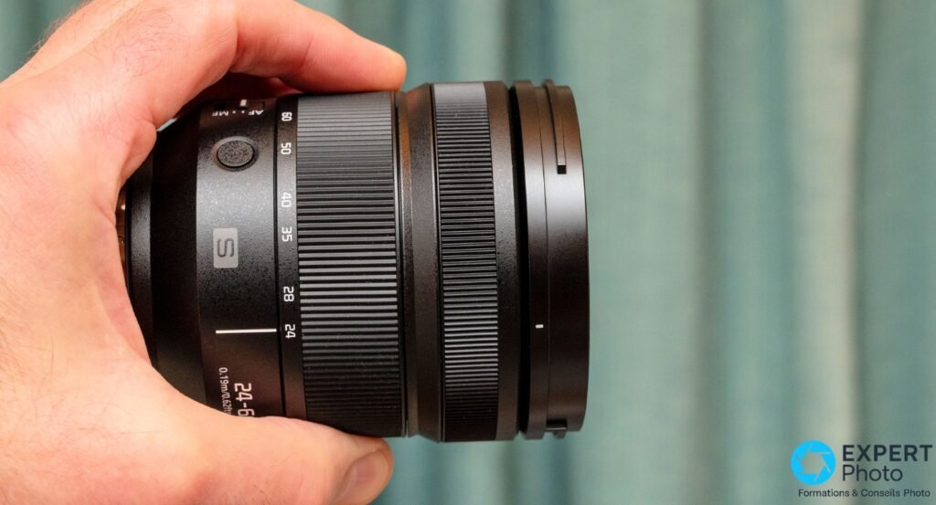 Objectif Panasonic Lumix S 24-60mm f/2.8 seul, profil côté droit, bague de zoom graduée 24-60, tenu en main
