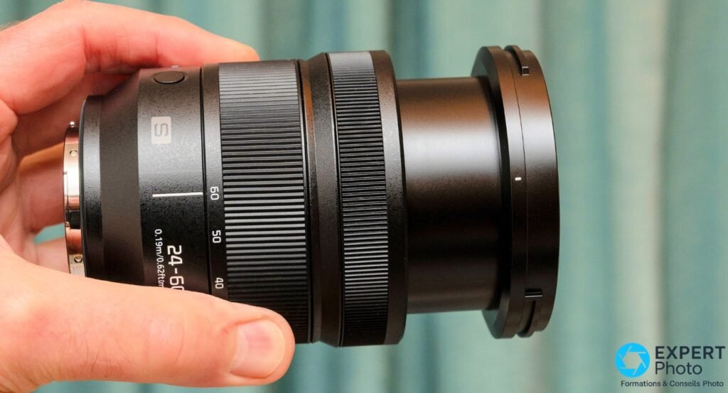 Objectif Panasonic Lumix S 24-60mm f/2.8 seul, profil côté monture L-Mount, bague graduée visible, tenu à deux mains