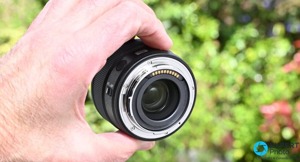 Objectif Panasonic Lumix S 40mm f/2 tenu en main, face arrière avec monture L-Mount et contacts électriques dorés visibles