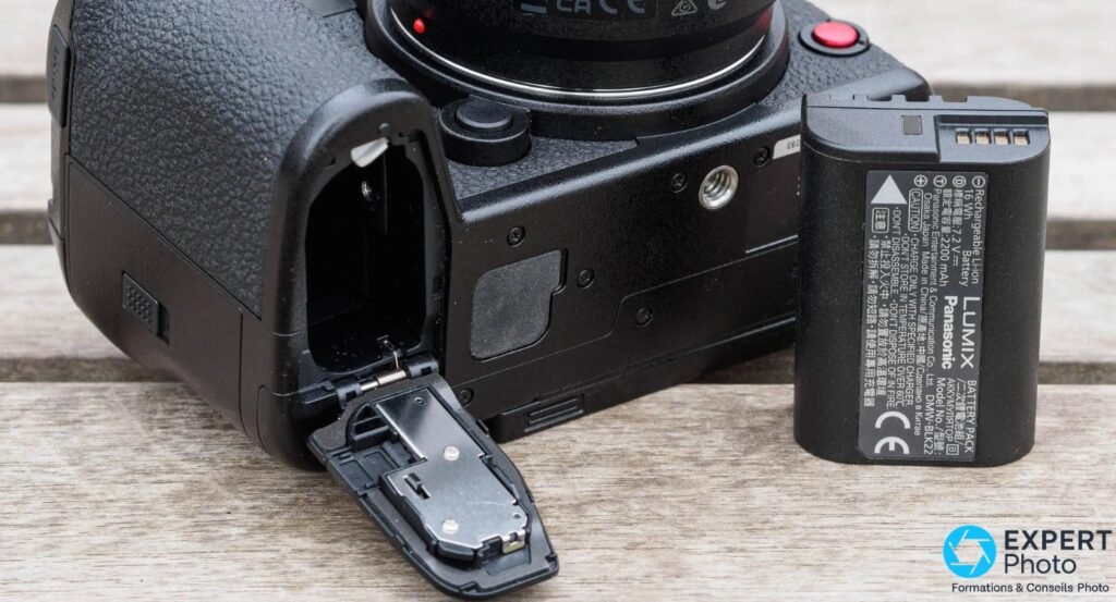  Panasonic Lumix S1R II dessous, trappe batterie ouverte, batterie Lumix DMW-BLK22 sortie posée à côté du boîtier 
