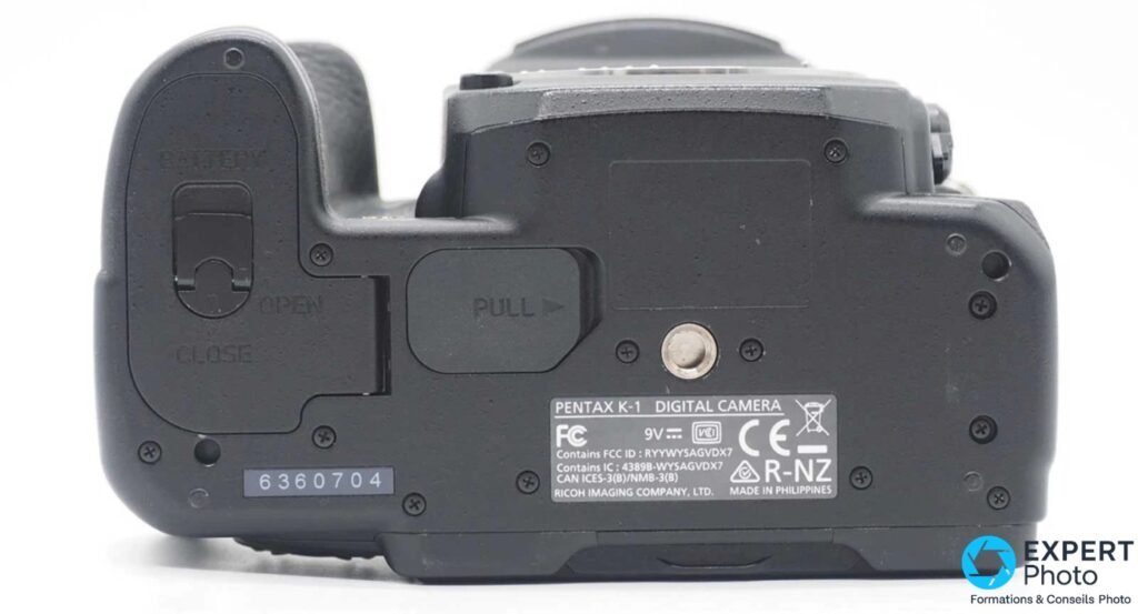 Pentax K-1 dessous, étiquette Ricoh Imaging MADE IN PHILIPPINES, trappe batterie OPEN/CLOSE et filetage trépied