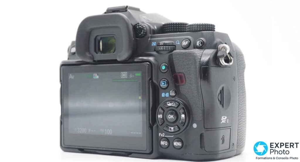 Pentax K-1 dos 3/4 gauche, écran LCD allumé en mode Av, viseur avec œilleton, boutons WB OK INFO MENU
