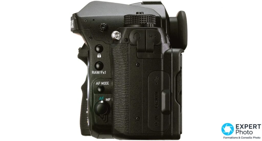 Pentax K-1 Mark II profil gauche, trappes fermées, boutons RAW/Fx1, AF MODE, sélecteur AF/MF sur la poignée