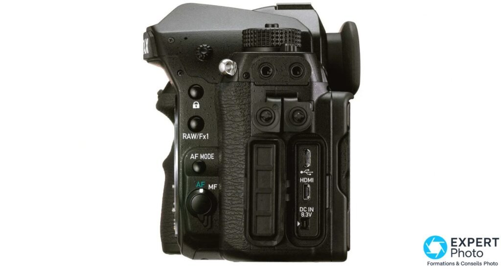 Pentax K-1 Mark II profil gauche, trappes ouvertes, ports HDMI, USB, DC IN 8.3V et deux prises audio visibles
