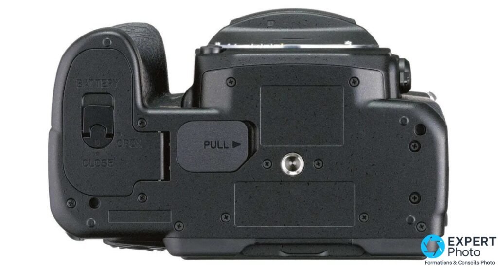 Pentax K-1 Mark II dessous, trappe batterie avec verrou OPEN/CLOSE, levier PULL du mécanisme d'écran orientable