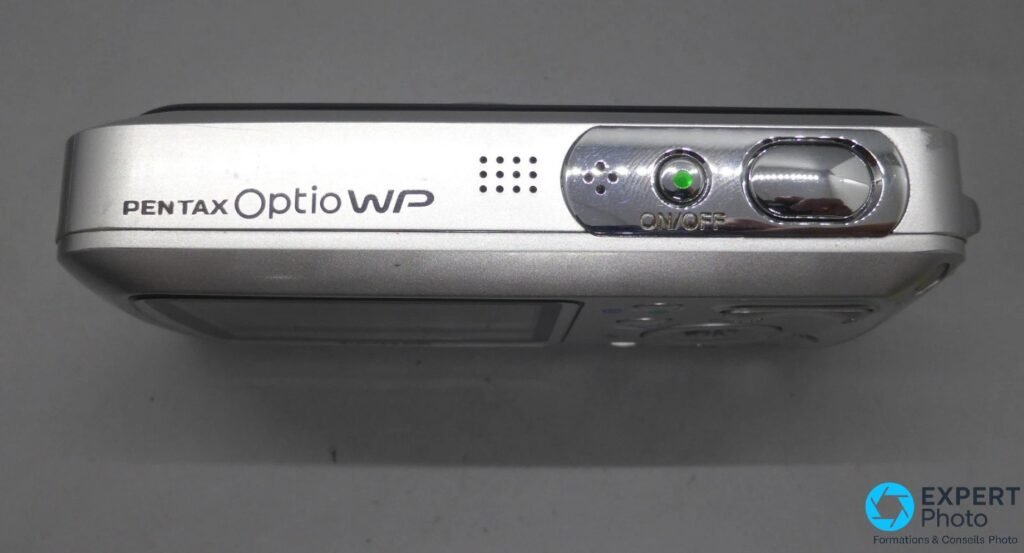 Pentax Optio WP argent, tranche supérieure, nom PENTAX Optio WP moulé, grille haut-parleur, bouton ON/OFF voyant vert