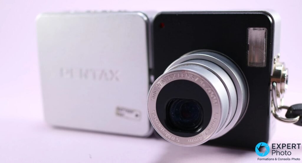 Face avant du module noir Pentax Optio X, objectif smc PENTAX LENS 3× ZOOM, f=5.8–17.4mm, 5.0 Megapixels, fond violet 