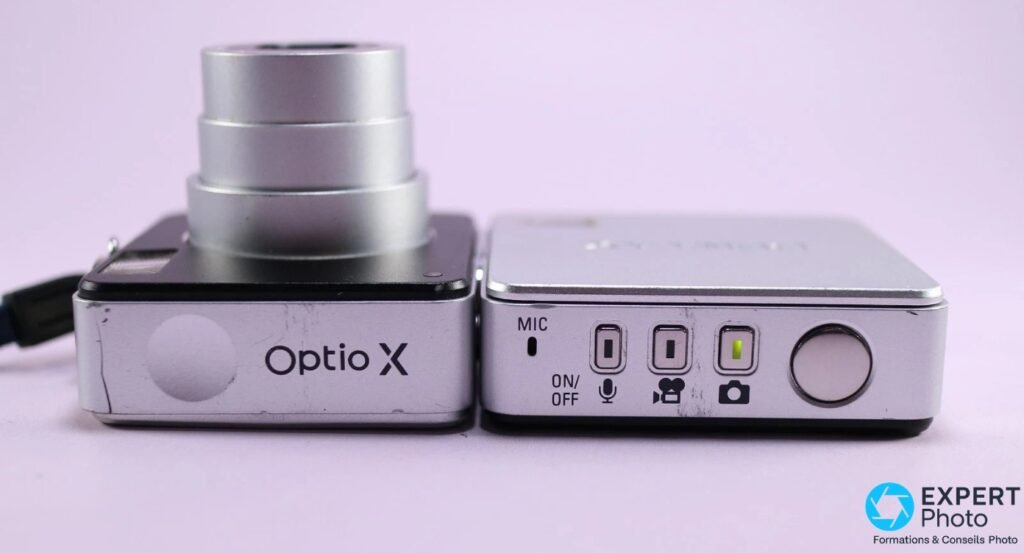 Vue de dessus du Pentax Optio X déplié, inscription Optio X, boutons ON/OFF, modes photo vidéo micro et déclencheur ronds argentés