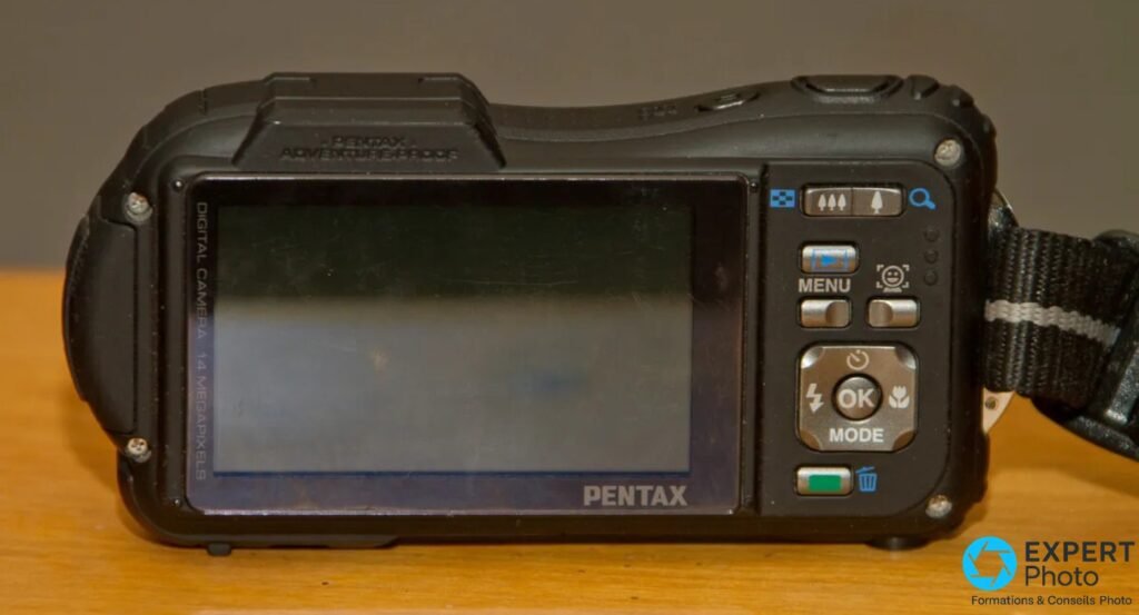 Pentax WG-1 dos : écran 2,7 po éteint, touches MENU, OK/MODE, navigation 4 directions, inscription ADVENTURE PROOF au dessus