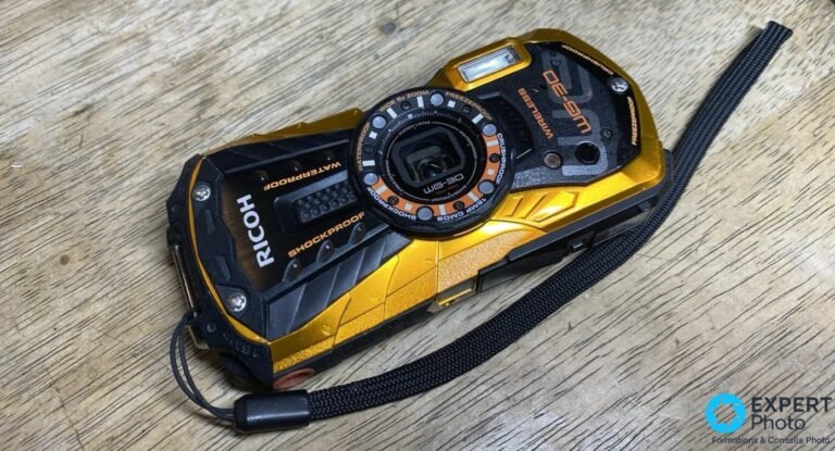 Ricoh WG-30W : baroudeur étanche d’ancienne génération Ricoh WG-30W jaune et noir, face avant 3/4, posé sur bois, objectif anneau LED, inscriptions Waterproof et Shockproof
