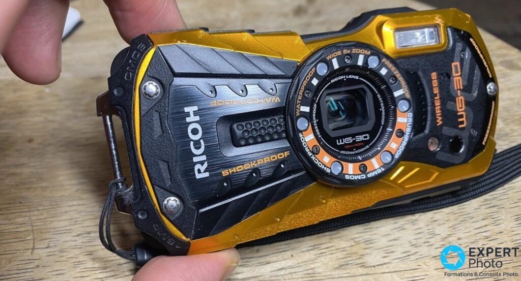 Ricoh WG-30W jaune et noir, face avant 3/4 tenu en main, objectif anneau LED, inscriptions Waterproof et WG-30