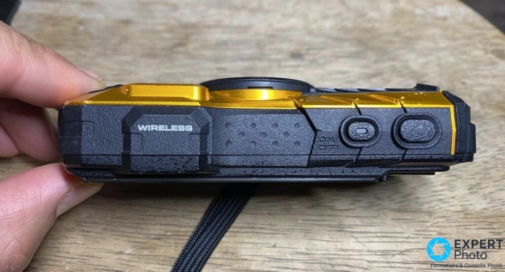 Ricoh WG-30W jaune et noir, tranche supérieure, inscription Wireless, boutons On/Off et déclencheur, fond bois