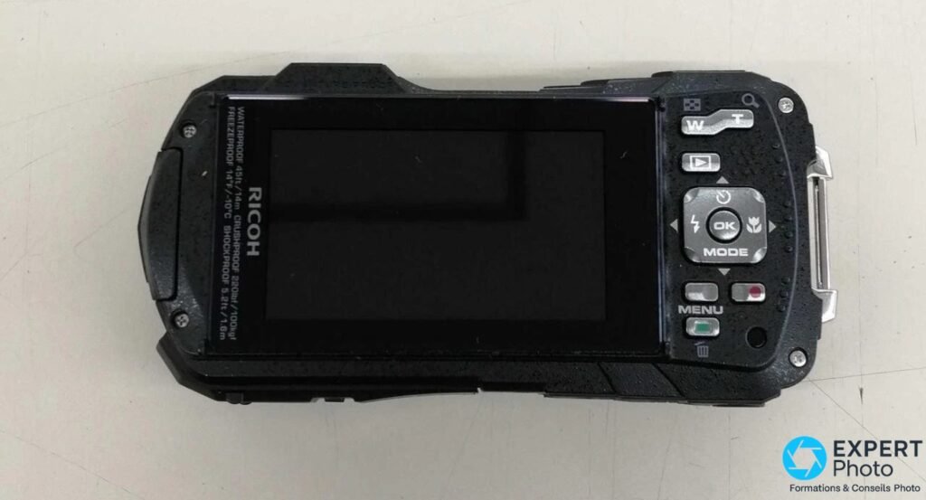 Ricoh WG-80 dos, écran LCD affichant certifications waterproof/crushproof, boutons OK MENU MODE navigation, gouttes d'eau