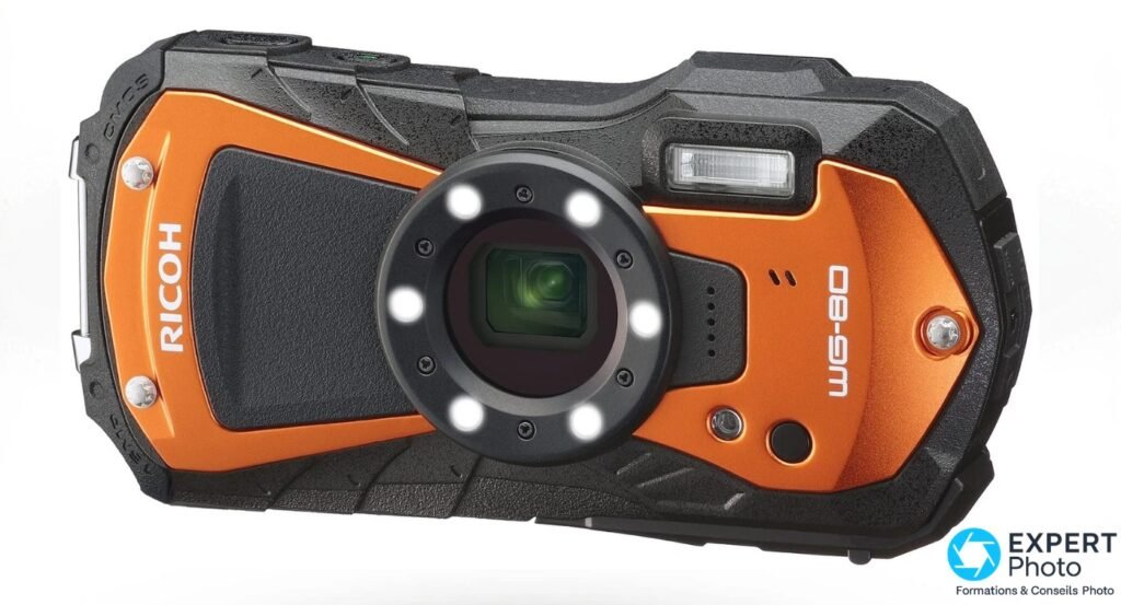 Ricoh WG-80 orange, vue 3/4 avant, anneau LED macro allumé autour de l'objectif, flash intégré visible
