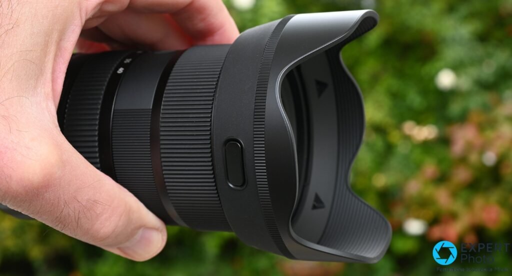 Sigma 17-40mm f/1.8 DC Art avec pare-soleil en pétale monté, vue profil gauche, bouton sur le fût visible