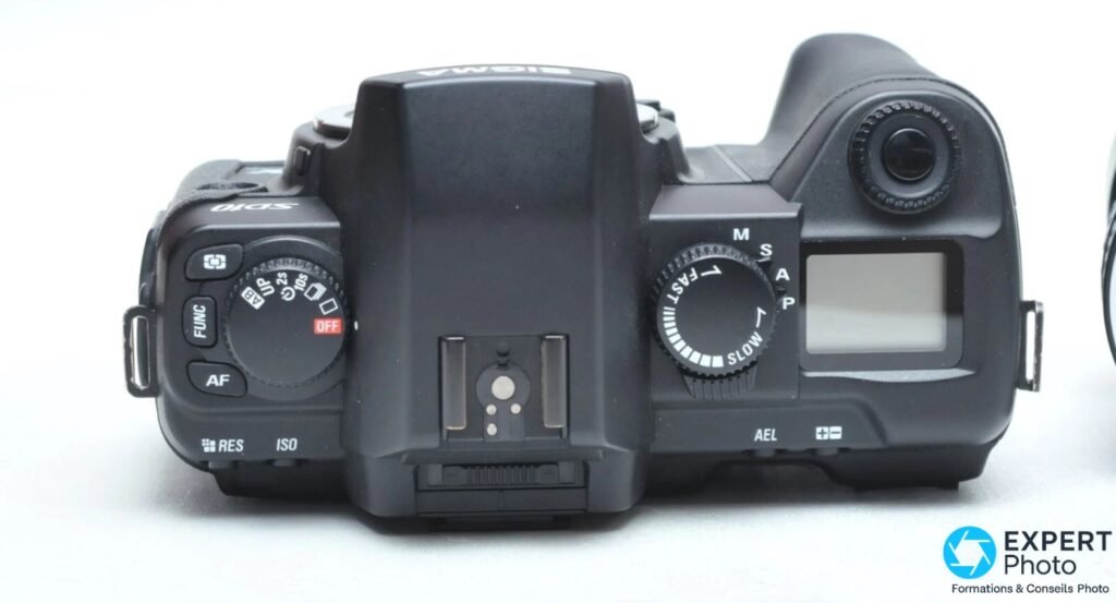 Sigma SD10 vu du dessus, molette modes M S A P, griffe flash centrale, boutons FUNC AF RES ISO et écran LCD de toit