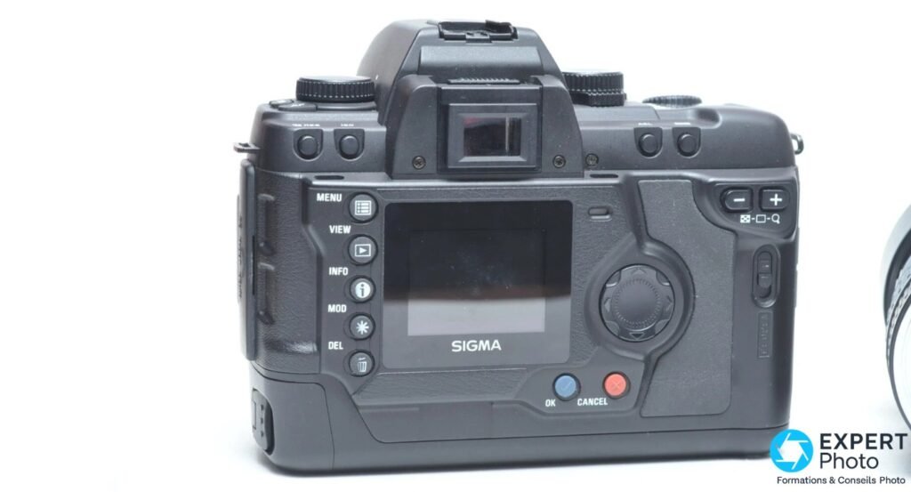Sigma SD10 vu de derrière, écran LCD éteint marqué Sigma, boutons de navigation et touches OK bleue et CANCEL rouge visibles