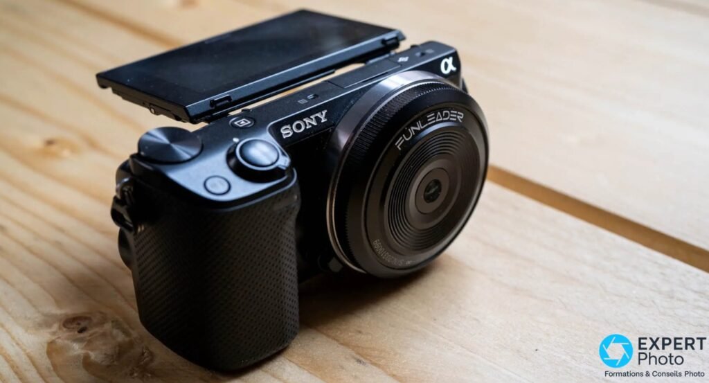Sony NEX-5R noir de 3/4, écran incliné éteint, objectif Funleader monture Sony E monté, sur fond de planches en bois 