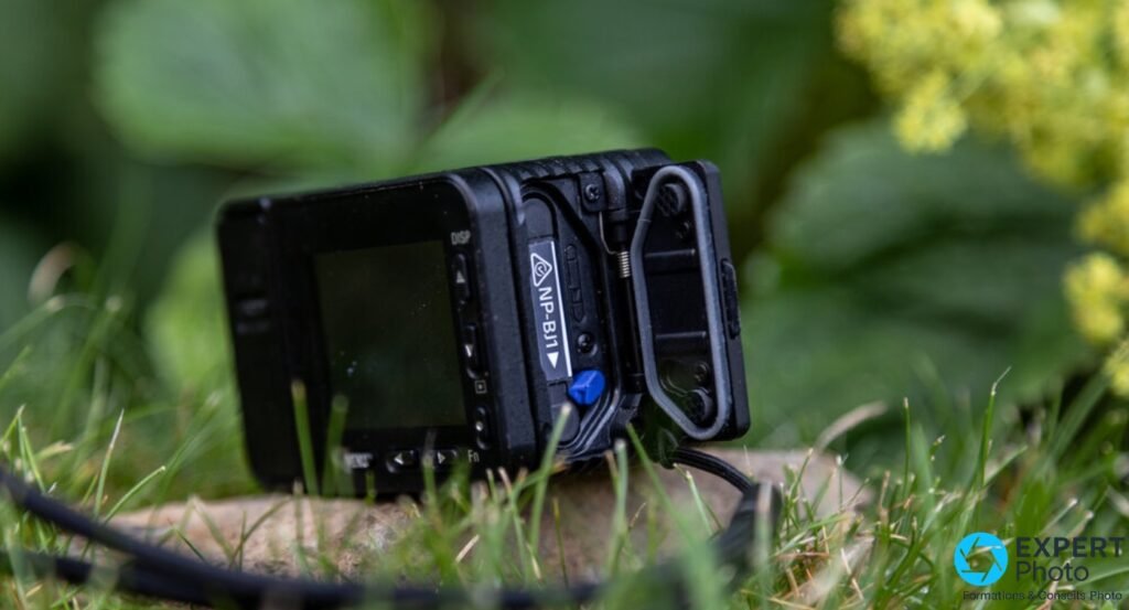 Sony RX0 II dos ouvert, batterie NP-BJ1 éjectée, languette bleue visible, écran et boutons DISP MENU Fn lisibles