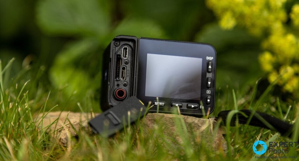Sony RX0 II vue latérale, écran inclinable actif, prise micro-jack rouge et ports de connexion, boutons MENU Fn DISP visibles