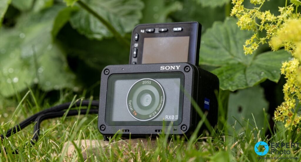 Sony RX0 II face avant dans l'herbe, protection optique verte montée, écran inclinable relevé, logos SONY et RX0 II 