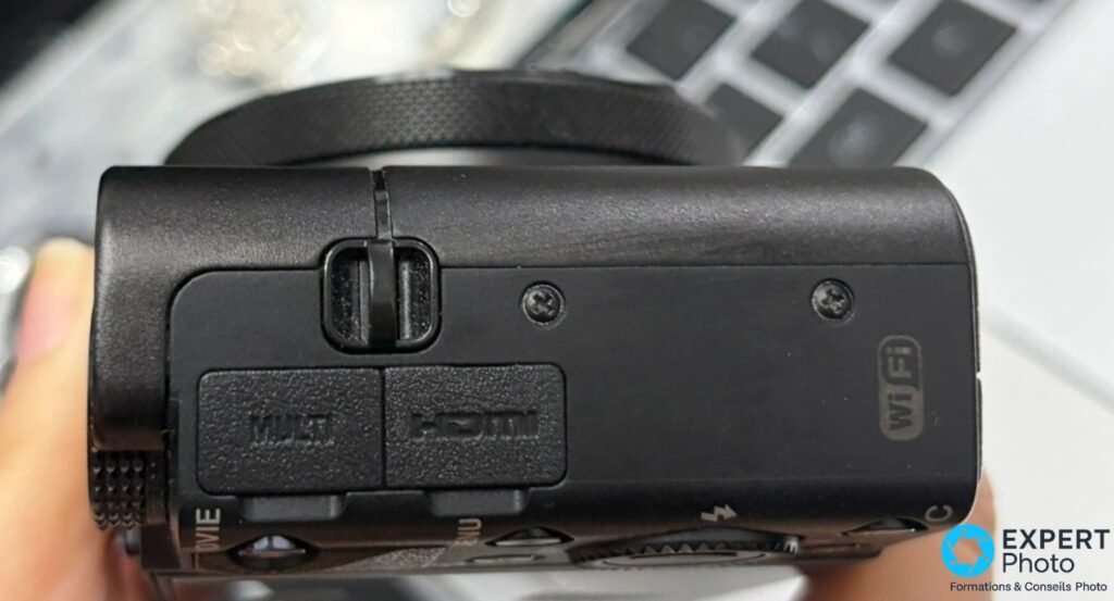 Profil droit du Sony RX100 VA avec trappes de connectique marquées MULTI et HDMI, logo Wi-Fi gravé sur le boîtier