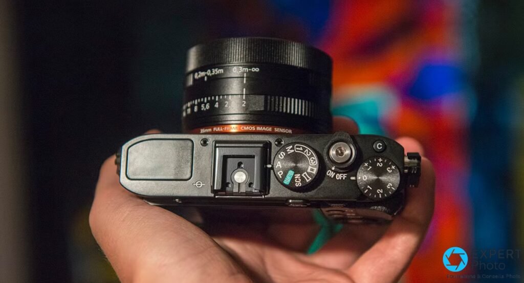 Sony RX1R tenu en main, vue de dessus : bague diaphragme graduée, molette modes S/A/P/M, anneau orange « 35mm Full-Frame CMOS Image Sensor » 