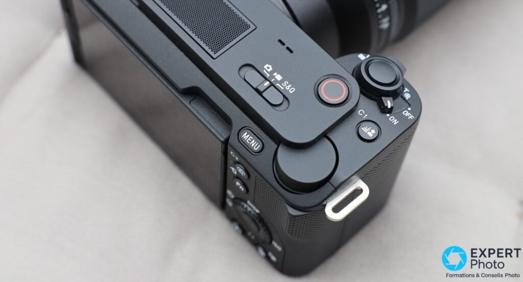 Sony ZV-E1 vue rapprochée du dessus : bouton enregistrement rouge, sélecteur S&O, commutateur ON/OFF, bouton C1 et microphone intégré à grille perforée