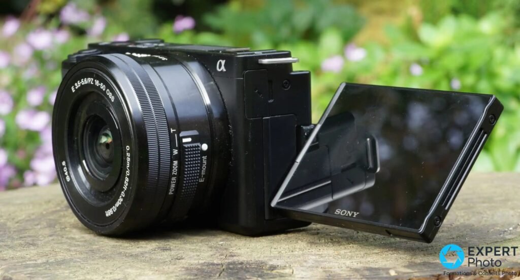 Sony ZV-E10 noir avec objectif E PZ 16-50 OSS, écran orientable retourné en position selfie, posé sur pierre