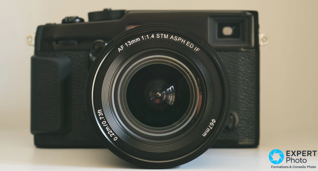 Viltrox AF 13mm f/1.4 XF de face, élément frontal 67mm, inscription AF 13mm 1:1.4 STM ASPH ED IF, reflets irisés dans la lentille, boîtier Fujifilm visible