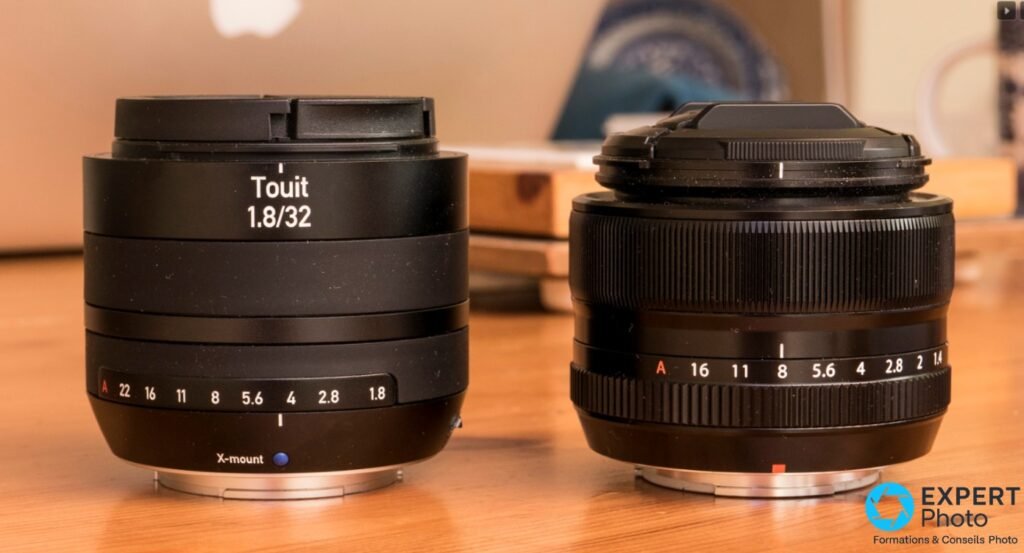 Zeiss Touit 1.8/32 X-mount à gauche et objectif Fujifilm X-mount à droite, bouchons avant montés, comparaison gabarit sur fond bois